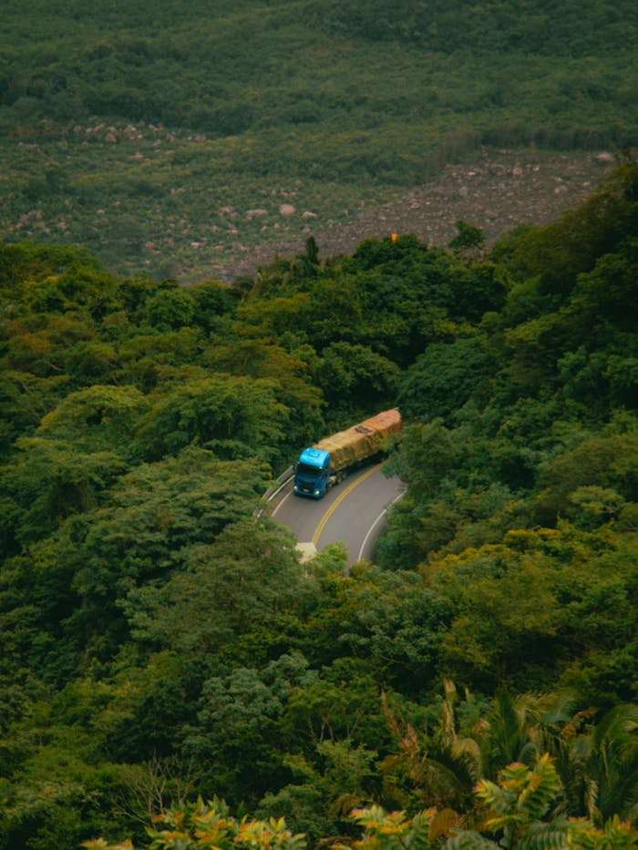 Aerial view of a truck navigating a winding mountain road through lush greenery in Tianguá, Brazil.
